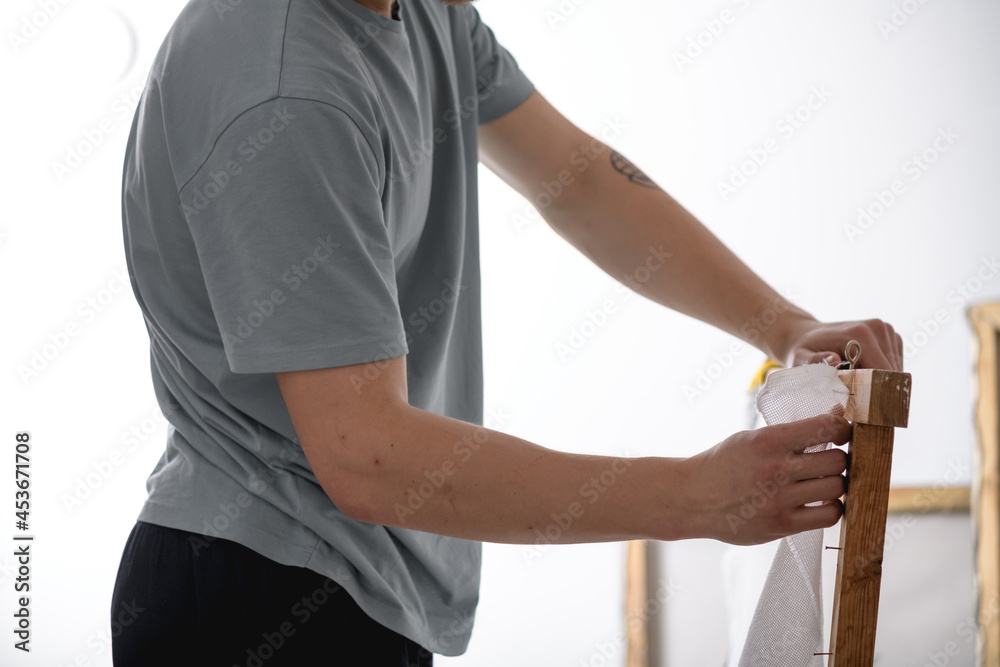 Obraz premium Cropped view of young artisan working with carpet canvas and wooden frame