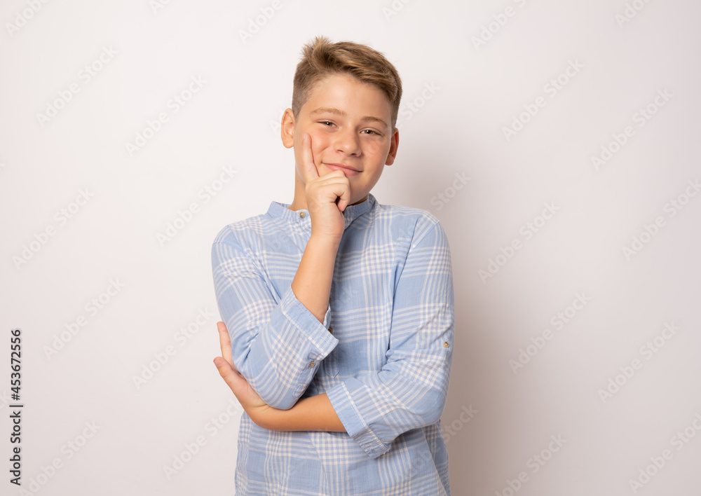 Pensive smiling boy in elegant shirt isolated over white background.