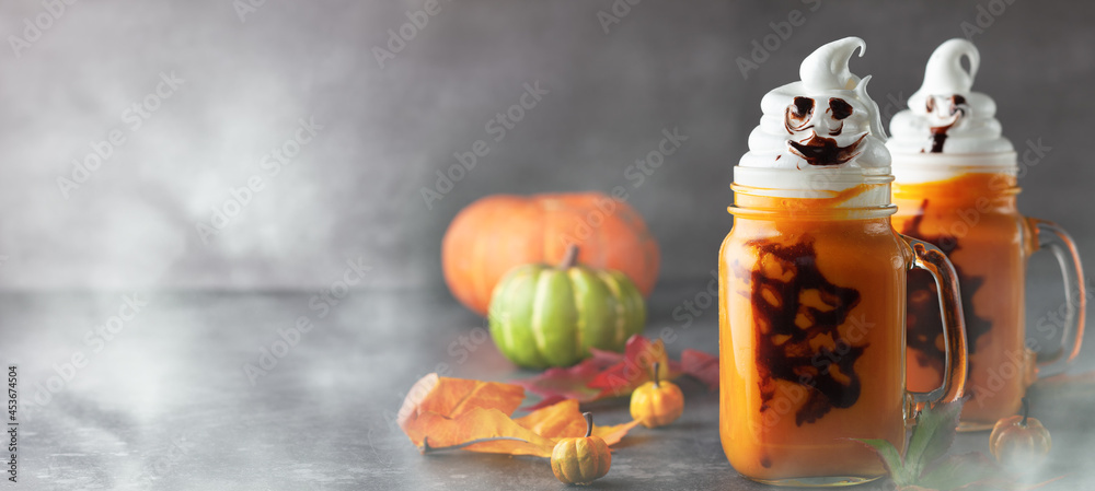 Halloween Pumpkin  cocktail with whipped cream in ghost shape and chocolate spider web. Freakshake for party.
