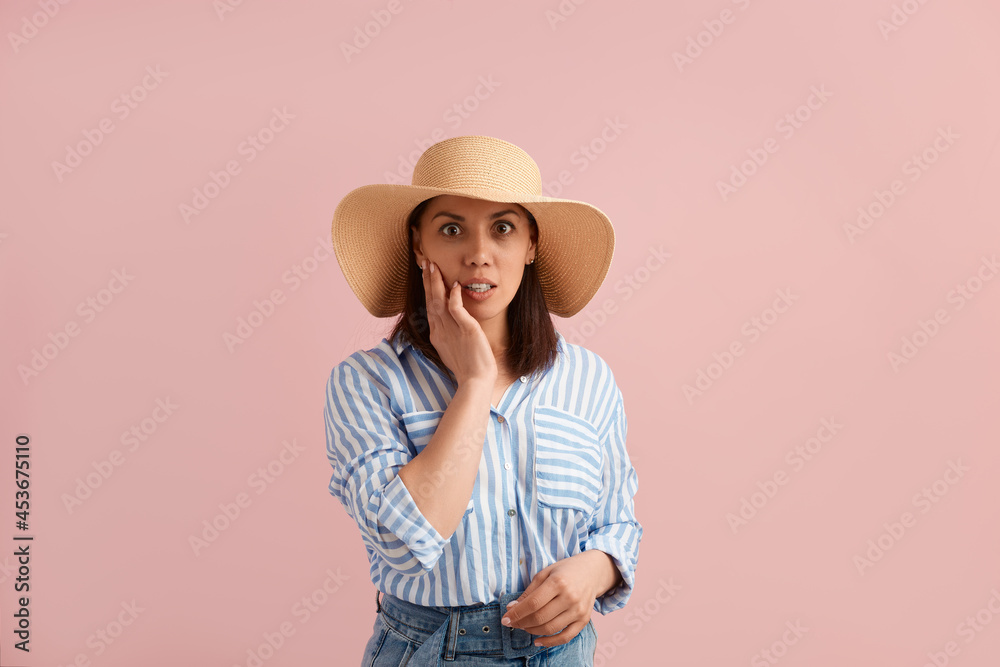 Oh no. Worried woman with dark forgot something, needs solution for improvement, to correct her mistake, wears straw hat, striped shirt, jeans with belt, on pink background. Summer emotions concept. Oh no. Worried woman with dark forgot something, needs solution for improvement, to correct her mistake, wears straw hat, striped shirt, jeans with belt, on pink background. Summer emotions concept.