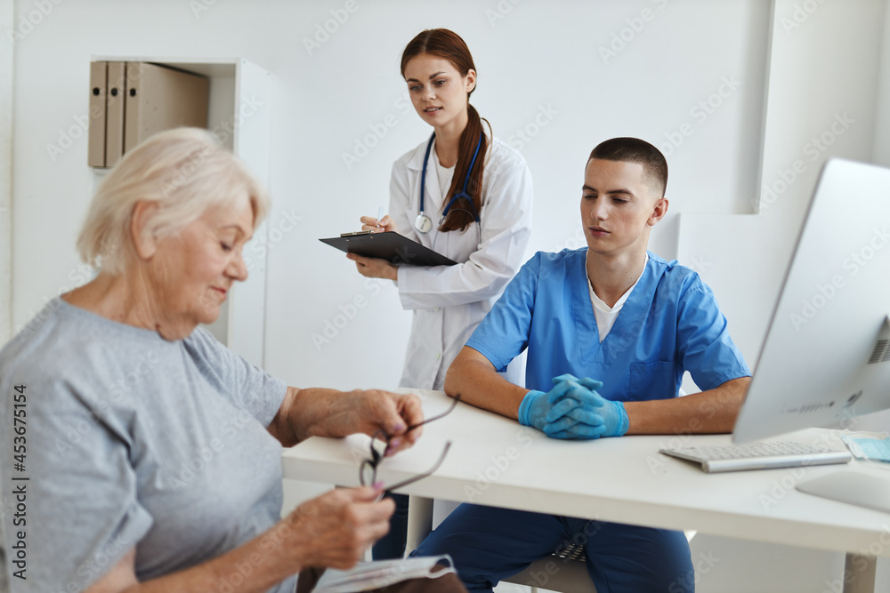 elderly woman patient at a reception in a medical office with a doctor nurse elderly woman patient at a reception in a medical office with a doctor nurse