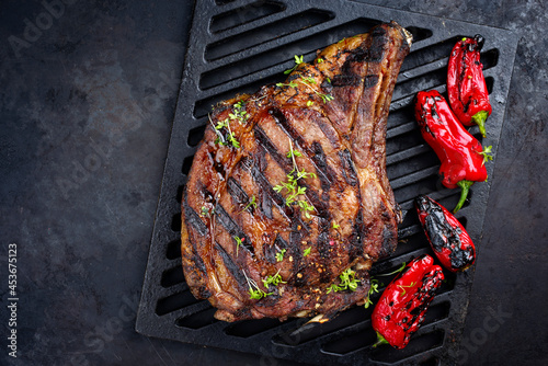 Traditional barbecue dry aged wagyu cote de boeuf beef steaks with zucchini and chili served as top view on a cast iron grillage with copy space left