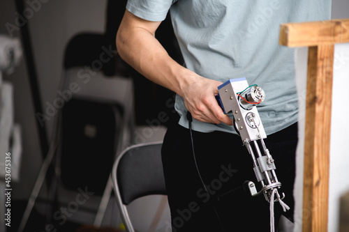 Cropped view of artisan with carpet tufting machine standing near wooden frame 