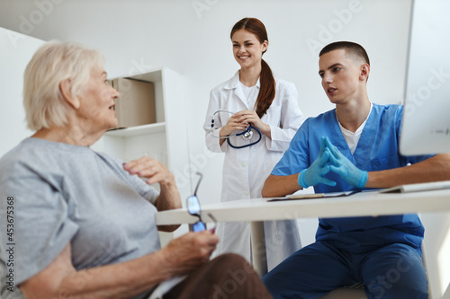 a nurse and a doctor talking to an elderly woman patient in a hospital