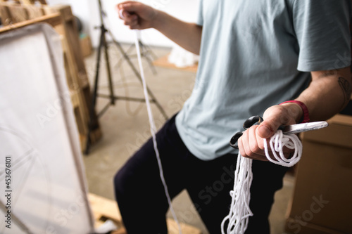 Cropped view of carpet maker holding scissors and thread near canvas on frame 