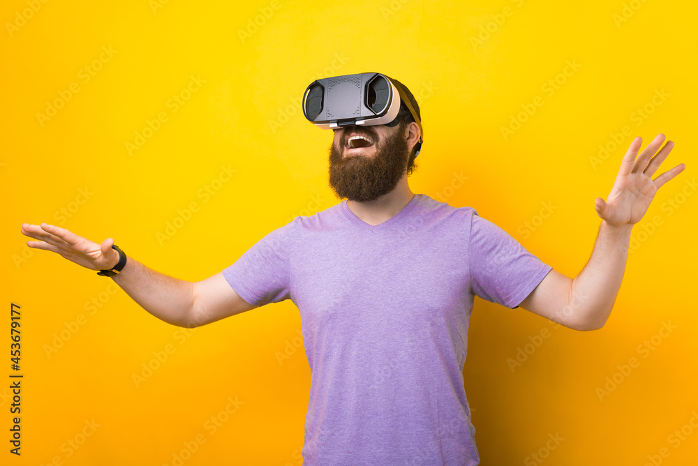 Bearded man is trying and enjoying his VR headset in a studio over yellow background. Bearded man is trying and enjoying his VR headset in a studio over yellow background.