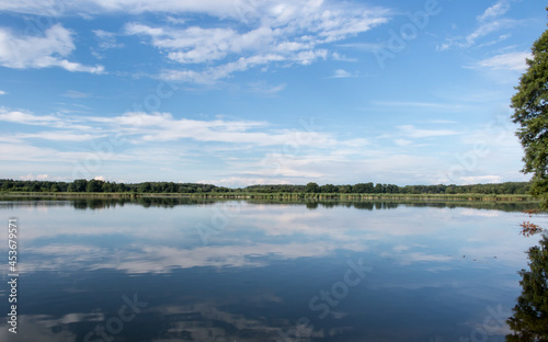 Fototapeta Naklejka Na Ścianę i Meble -  Blue sky covered with white clouds and sky reflection in the calm water of Pilka lake