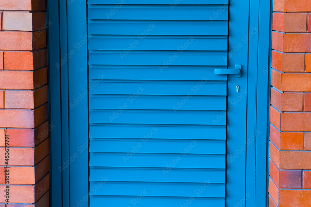 Fototapeta premium Photo of a blue painted wooden door on a red brick wall.