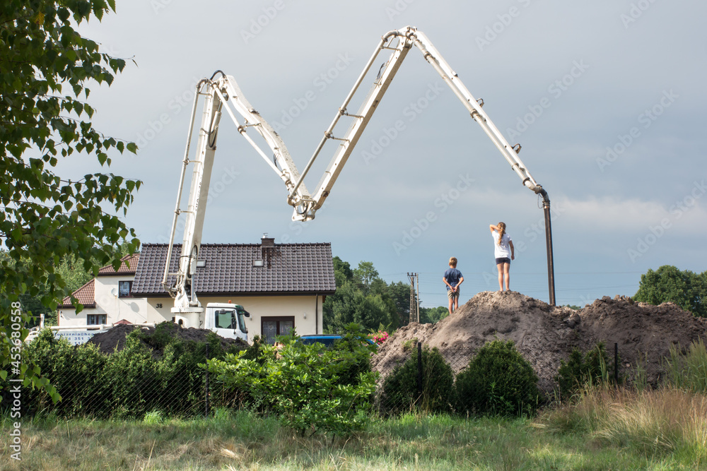 children watch concrete pouring from a truck concrete mixer to the foundation of a new house children watch concrete pouring from a truck concrete mixer to the foundation of a new house