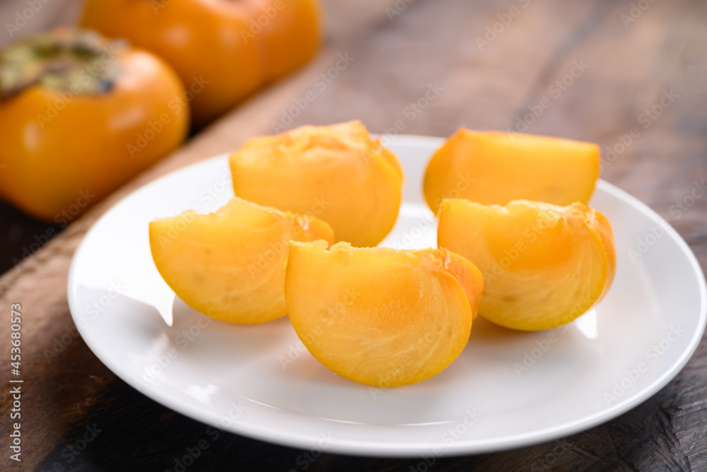 Sliced persimmon fruit on white plate ready to eating