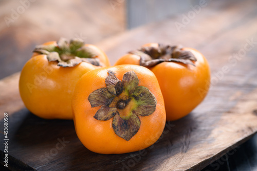 Ripe persimmon fruit on wooden background photo