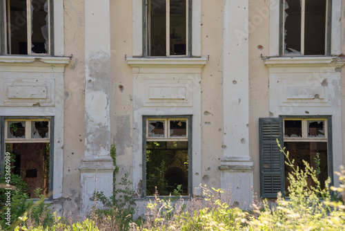 Damaged wall with broken windows and bullet holes. Abandoned tourist resort in Kupari, Croatia.  photo
