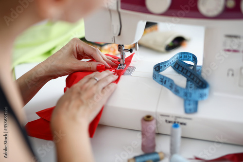 Woman sew on red fabric on a sewing machine photo
