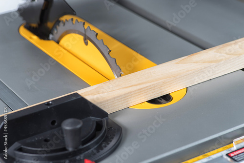 close up cuts a piece of pine wood pushing the cross cut fence on a table saw