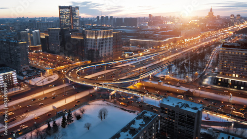 View from above to Moscow multi-level highway in winter lit by the sunset light. Camera showing panorama of the evining city and then coming closer to the junction with a lot of traffic. photo