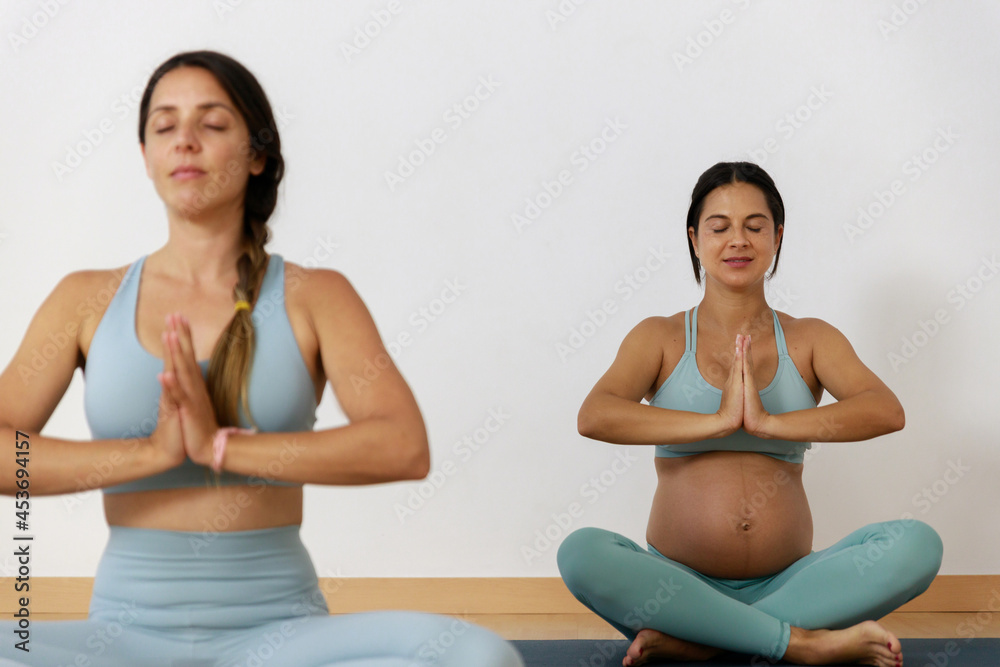 Pregnant woman doing yoga with a yoga teacher 