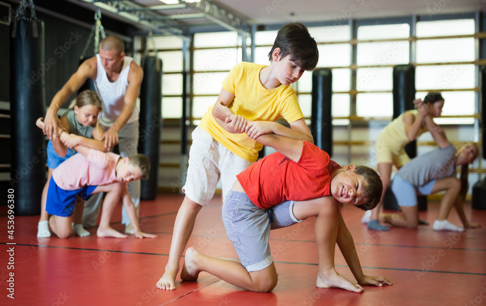 Obraz premium Two preteen boys in pair practicing self-protection during group class at gym