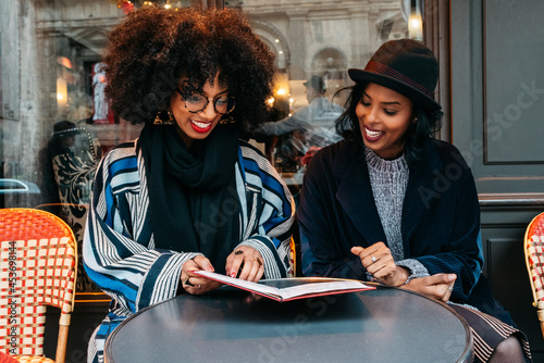 two Black women looking at a restaurant menu