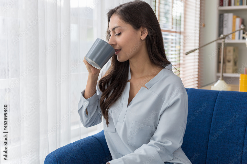 Young caucasian woman sitting sofa enjoying first morning coffee.