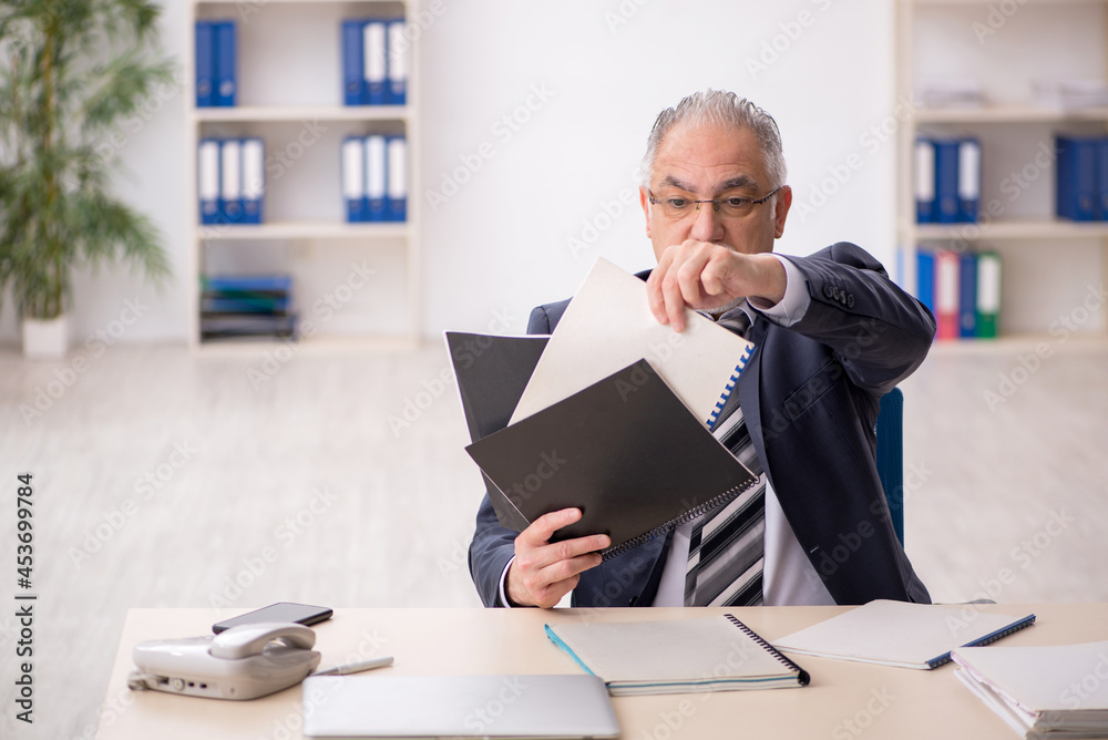 Old male employee working in the office