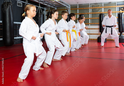 Kids in kimonos practicing effective karate techniques in group workout at training room