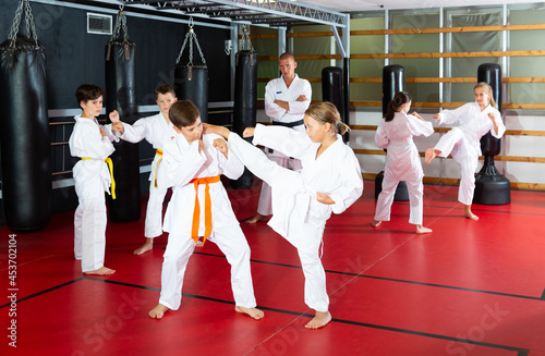 Sportive children working in pair mastering new karate moves during group class