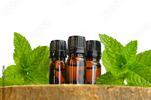 Peppermint essential oil isolated on white background.Glass bottles and sprigs of mint on a wooden saw cut close-up.Organic pure peppermint oil.Natural bio cosmetics 