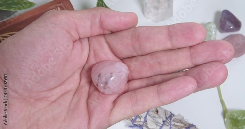 Pink Petalite tumbled stone in the palm of a hand photo