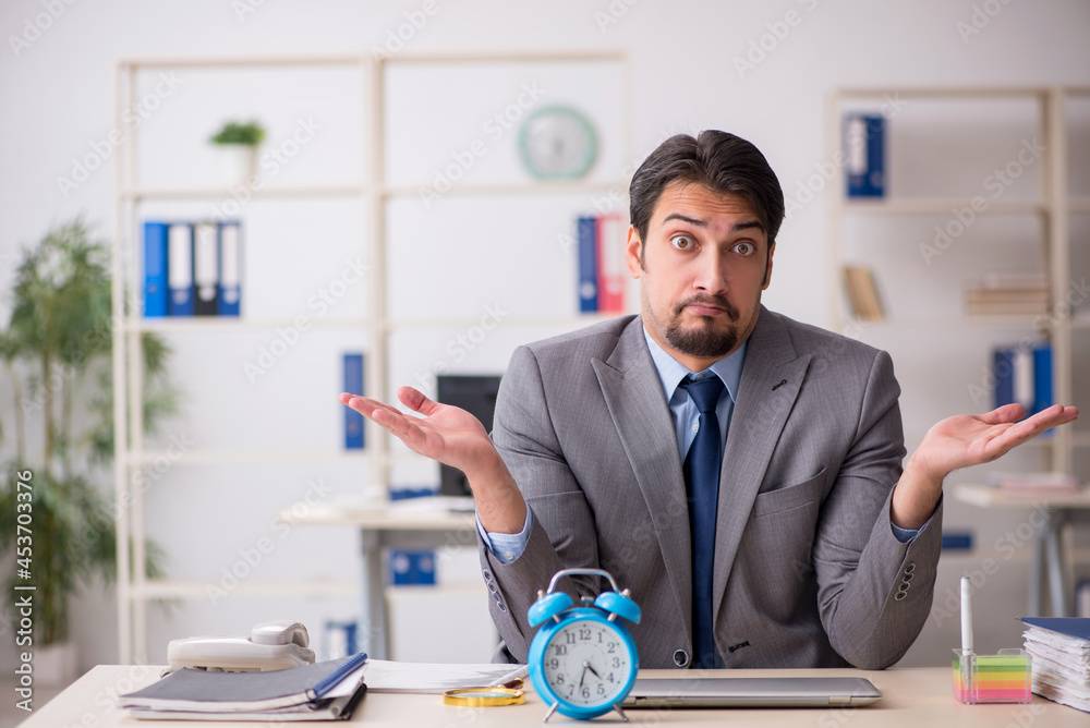 Young male employee in time management concept Young male employee in time management concept