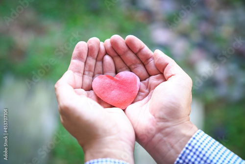 Hand holding red heart. Heart health insurance, organ donation, volunteer and charity concept.