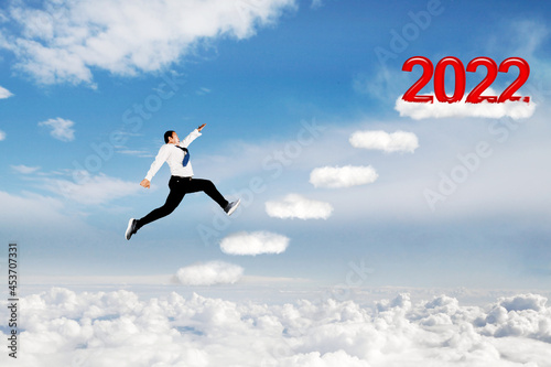 Businessman running on clouds toward 2022 numbers