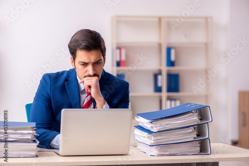 Young male employee unhappy with excessive work in the office