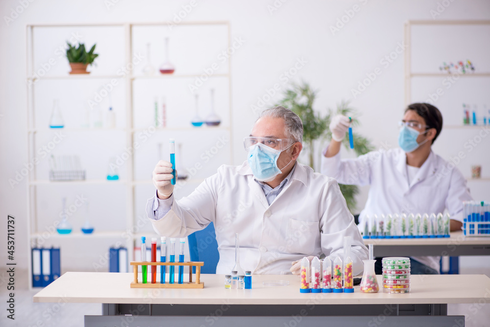 Two male chemists in drugs synthesis concept at the lab Two male chemists in drugs synthesis concept at the lab