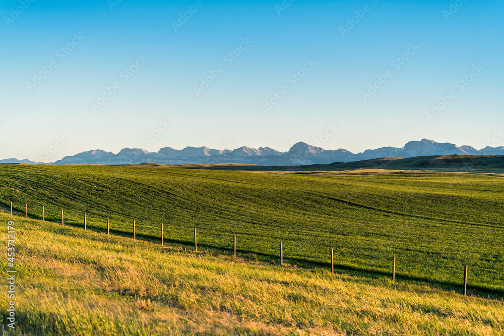 Typical panorama of Montana landscape at sunset. Scenic view with fence and mountains in background. Clear sky