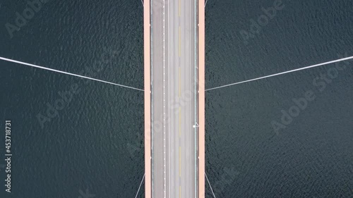 Mighty Cables holding suspension bridge Hardangerbrua - Forward moving birseye aerial over bridge with cables passing close - Hardangerfjorden sea below - Norway photo