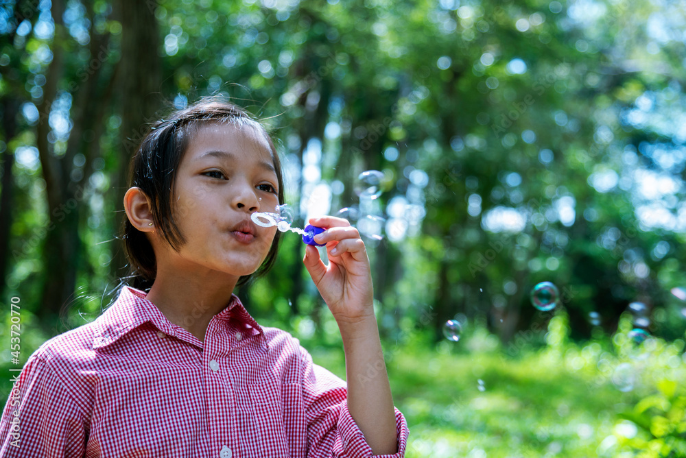 Adorable happy cute girl playful foam bubbles in green playground in summer outdoors. Funny Cheerful girl in the park with happy times. Adorable happy cute girl playful foam bubbles in green playground in summer outdoors. Funny Cheerful girl in the park with happy times.