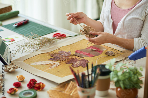 Hands of woman decorating oshibana style artwork with flowers made of flax rope photo