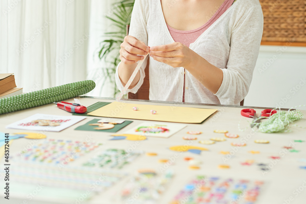 Hands of woman making stars out of colorful paper stripes when creating greeting cards at home Hands of woman making stars out of colorful paper stripes when creating greeting cards at home