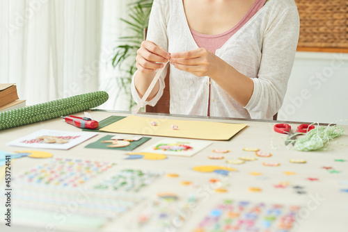 Hands of woman making stars out of colorful paper stripes when creating greeting cards at home