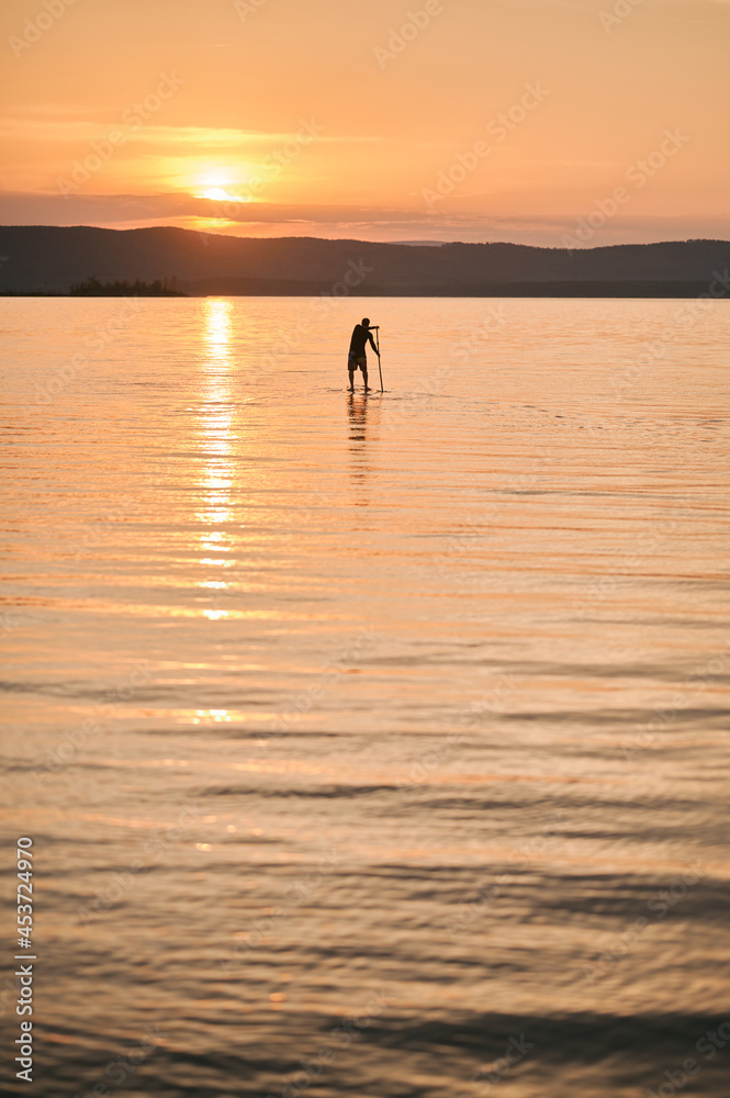 Man paddling on sup surf on sunset