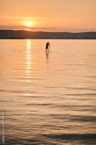 Man paddling on sup surf on sunset