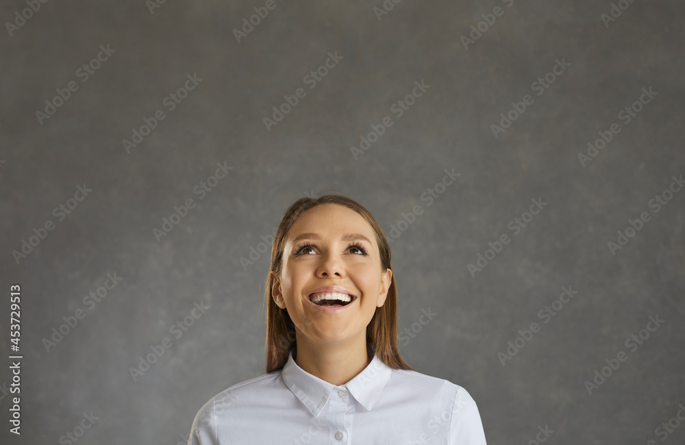Amazed happy young caucasian woman looking up and thoughtfully smiling studio shot portrait. Cheerful carefree girl student daydreaming. People emotion and pleasant feeling concept Amazed happy young caucasian woman looking up and thoughtfully smiling studio shot portrait. Cheerful carefree girl student daydreaming. People emotion and pleasant feeling concept