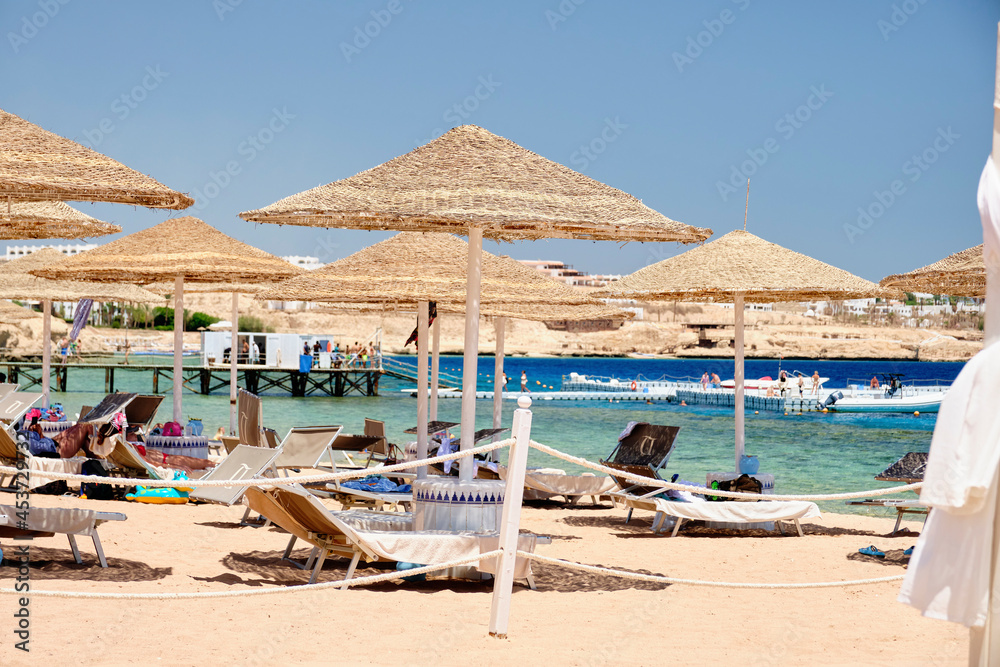 Sun loungers with umbrellas on the beach for a relaxing holiday on the background of the sea