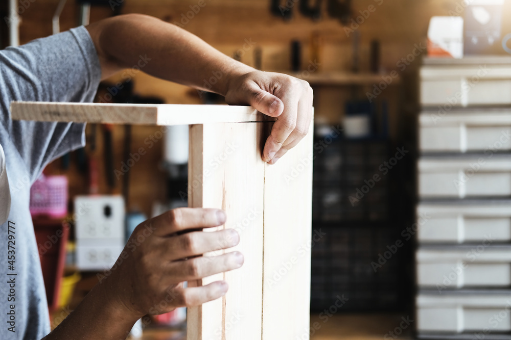 Obraz premium A carpenter measures the planks to assemble the parts, and build a wooden table for the customer.