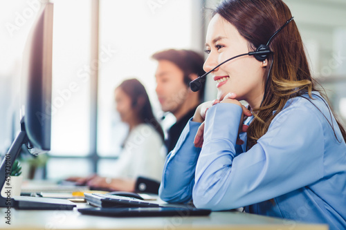 Close up beautiful woman customer service with headset working with team in call center. Young Asian businesswoman pay attention and talking to customer while using computer at office.