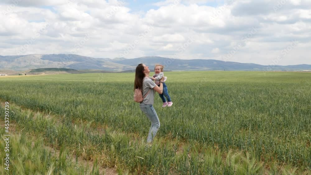 Happy young mother playing outdoors with her little baby
