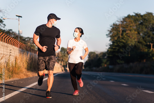 Young Asian athletic friends running outdoor while wearing face protective masks during coronavirus outbreak. Healthy lifestyle and sport in the days of coronavirus and covid-19.
