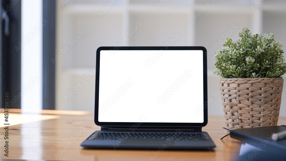 Mock up computer tablet with white display, houseplant and notebook on wooden desk. Mock up computer tablet with white display, houseplant and notebook on wooden desk.