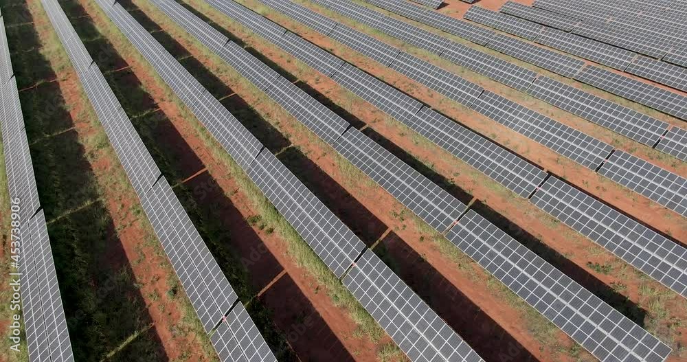 Hundreds of solar energy panels are in rows along with the dry lands. an aerial drone point of view during a colorful sunset. Green energy solar plates creating energy