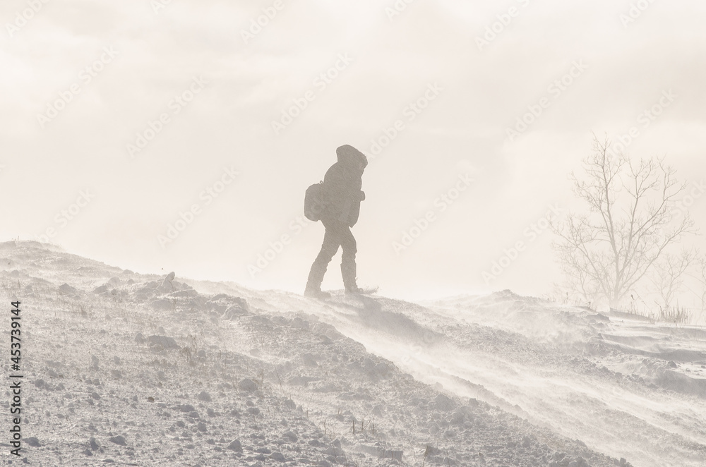 A man with a backpack goes in a cold winter blizzard.